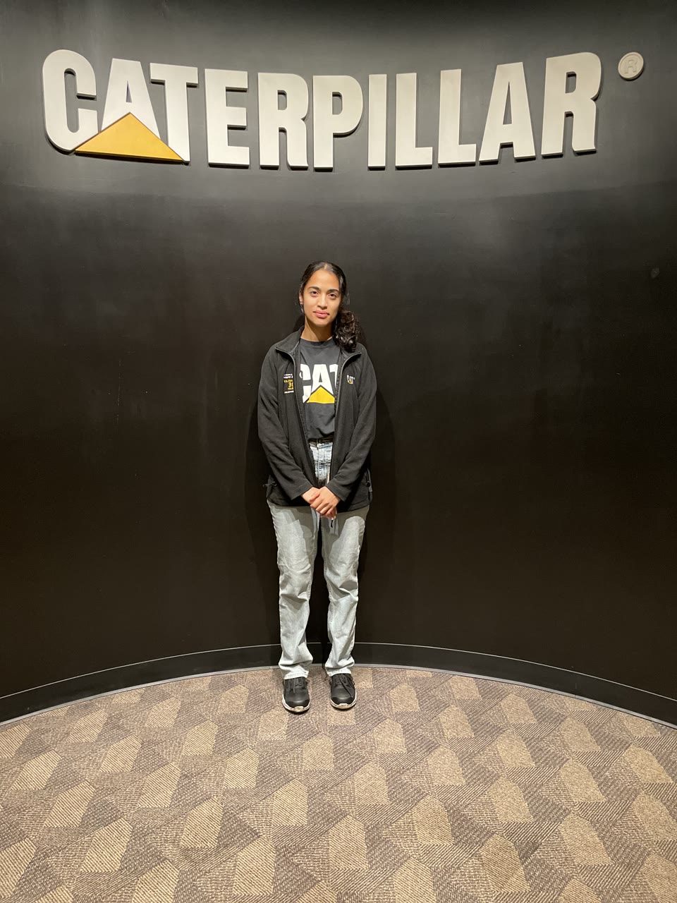 Hazel Mohamedali at Caterpillar Hazel Mohamedali standing beneath the Caterpillar sign